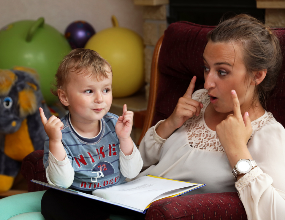 lille dreng sidder ved kvinde og bliver undervist