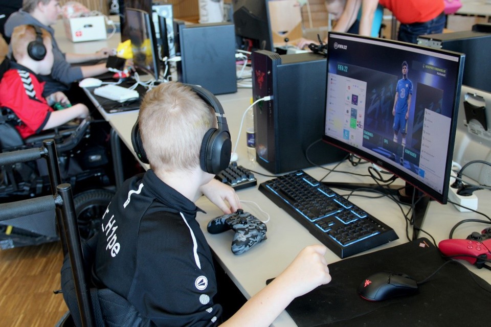 To drenge (den ene i kørestol) spiller e-sport på computere