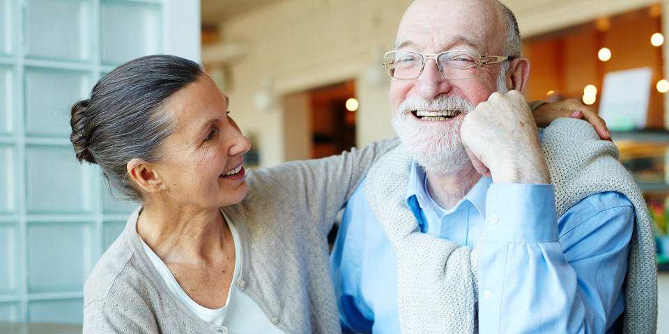 Ældre kvinde og mand sidder ved kaffebord og ler