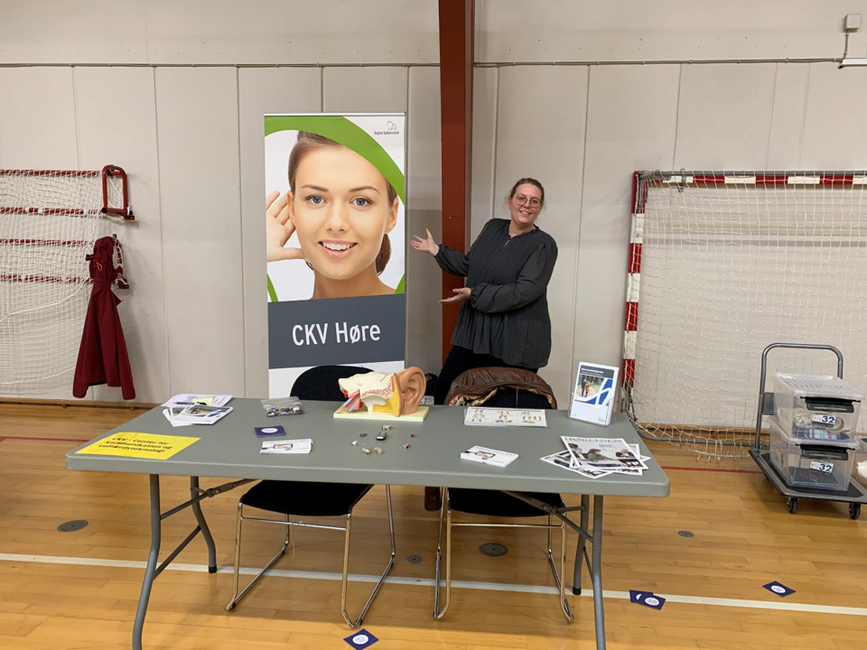 Smilende kvinde står i en stand på Seniorlivsmessen