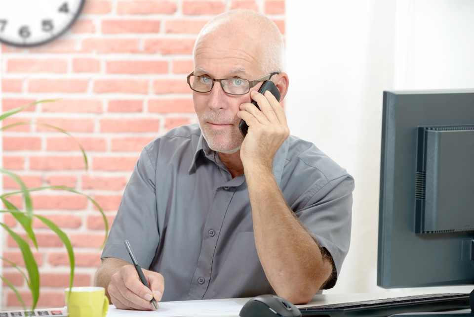 mand sidder og taler i telefon
